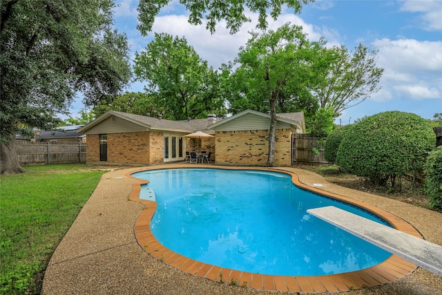 view of pool with a lawn, a diving board, and a patio