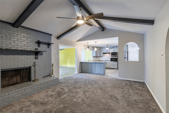 unfurnished living room featuring a brick fireplace, sink, ceiling fan, vaulted ceiling with beams, and carpet floors