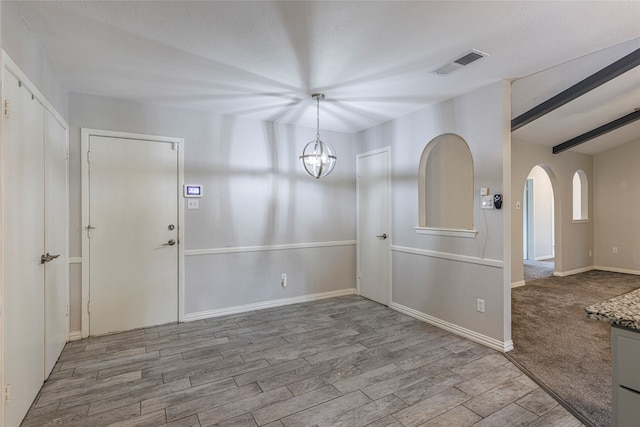 interior space featuring lofted ceiling with beams and light hardwood / wood-style flooring