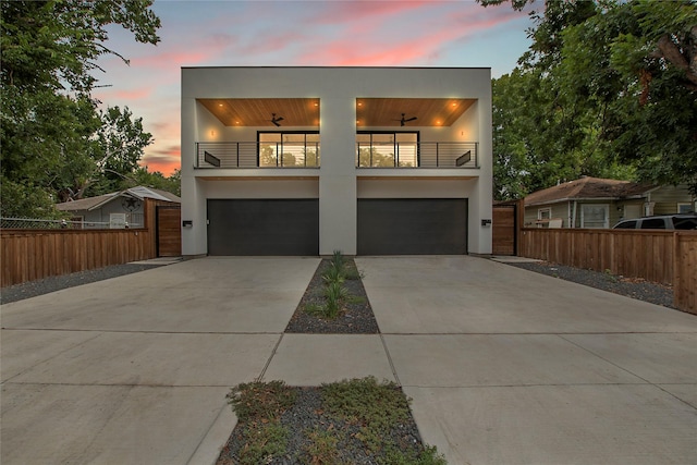 contemporary home featuring a balcony, fence, and stucco siding