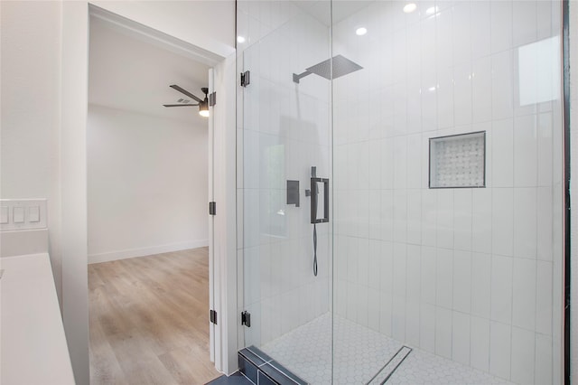 full bathroom with a stall shower, baseboards, wood finished floors, and a ceiling fan