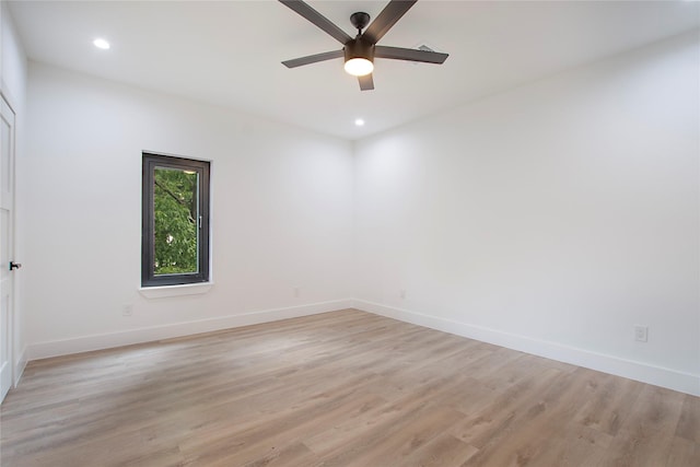 spare room with baseboards, light wood finished floors, and ceiling fan