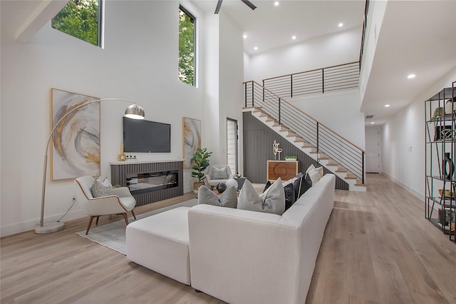 living room with baseboards, wood finished floors, a glass covered fireplace, and stairway