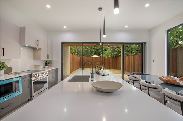 kitchen featuring decorative light fixtures, a healthy amount of sunlight, stainless steel appliances, and sink