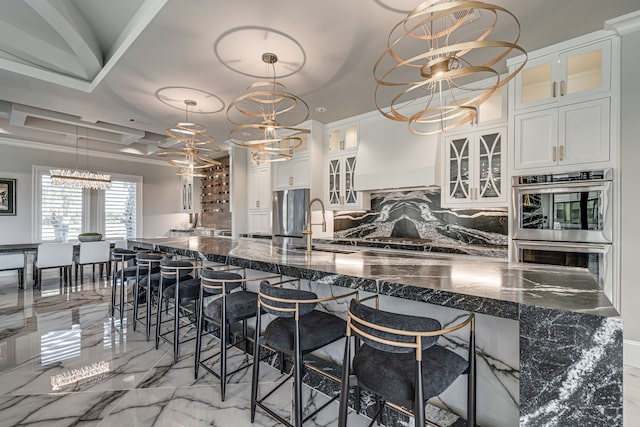 kitchen featuring hanging light fixtures, a breakfast bar area, a notable chandelier, and white cabinets