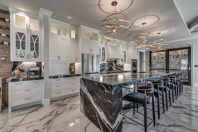 kitchen featuring an inviting chandelier, appliances with stainless steel finishes, hanging light fixtures, white cabinetry, and a large island