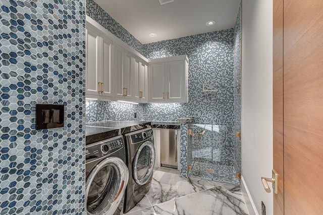 clothes washing area featuring cabinets and washing machine and dryer