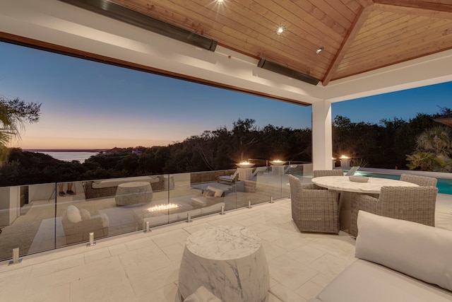 patio terrace at dusk with an outdoor fire pit, a gazebo, and a water view