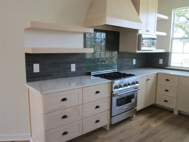 kitchen with light stone countertops, custom range hood, wood-type flooring, stainless steel appliances, and decorative backsplash