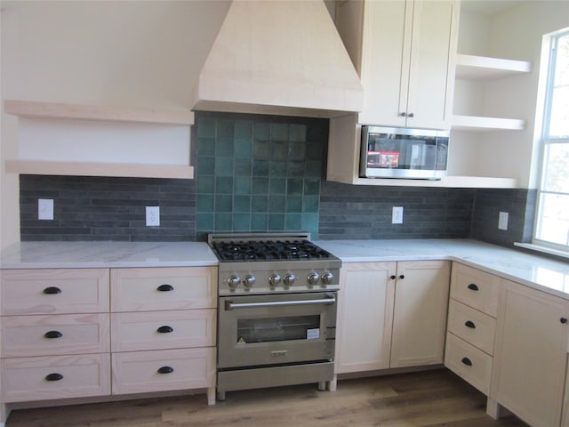 kitchen featuring open shelves, plenty of natural light, stainless steel appliances, custom range hood, and light wood-type flooring
