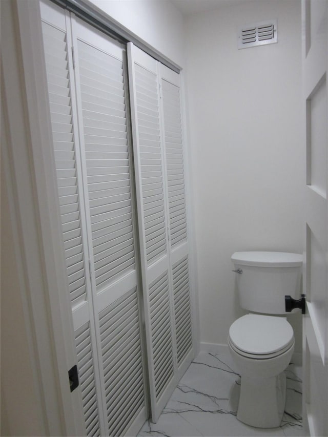 bathroom featuring toilet, baseboards, visible vents, and marble finish floor