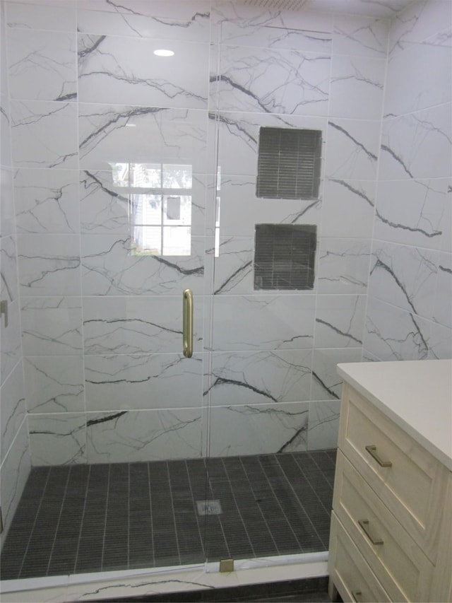full bathroom with a marble finish shower, vanity, and visible vents