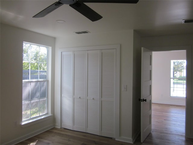 unfurnished bedroom with multiple windows, wood finished floors, and visible vents