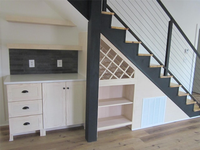stairway featuring wood finished floors and visible vents