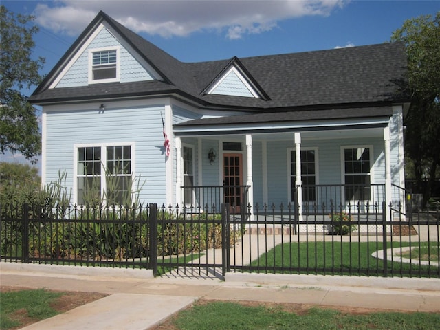 view of front of property featuring a shingled roof, a front lawn, a fenced front yard, and covered porch