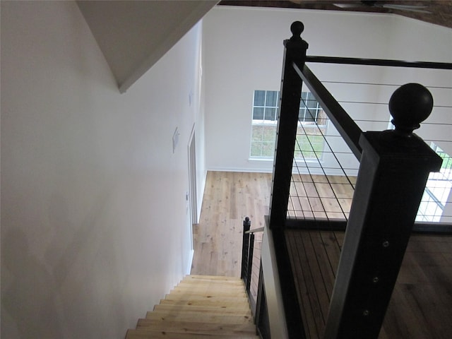 stairs with wood finished floors and lofted ceiling