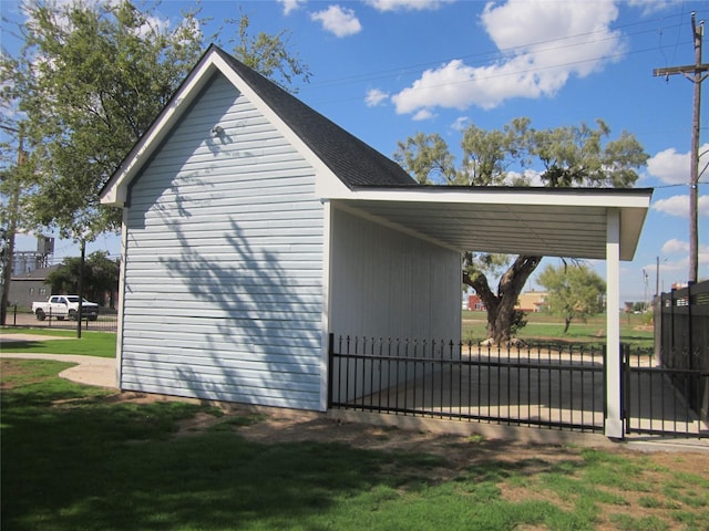 view of side of home with fence, a carport, and a lawn