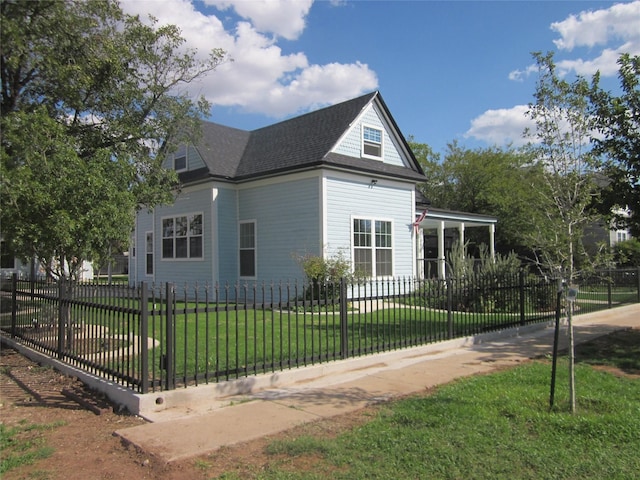 view of side of property featuring a lawn, a fenced front yard, and a shingled roof