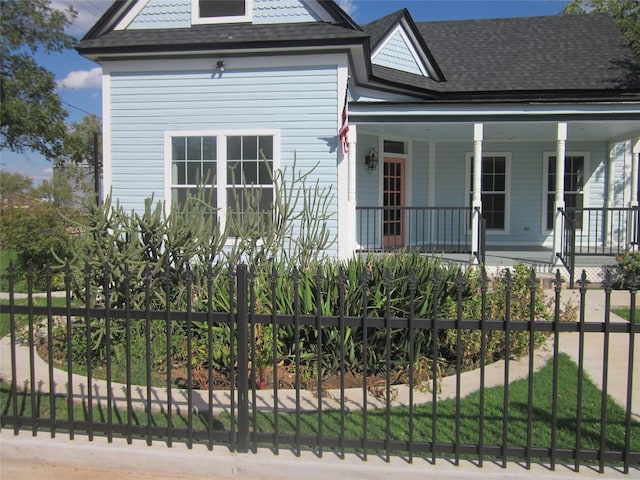 view of front of property featuring a porch, roof with shingles, and fence