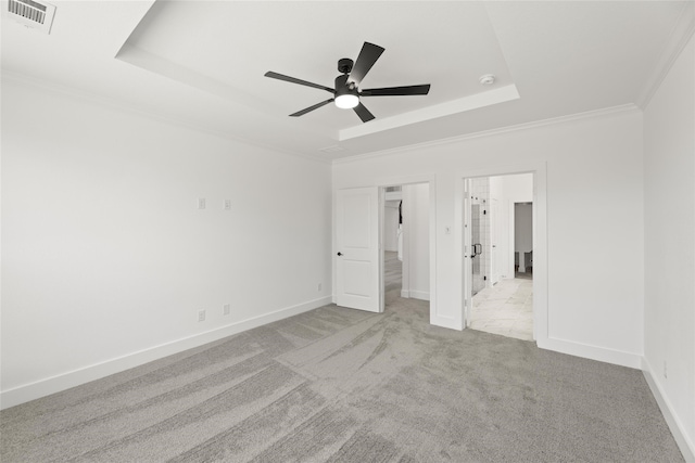 unfurnished bedroom with ornamental molding, a tray ceiling, light colored carpet, and ceiling fan