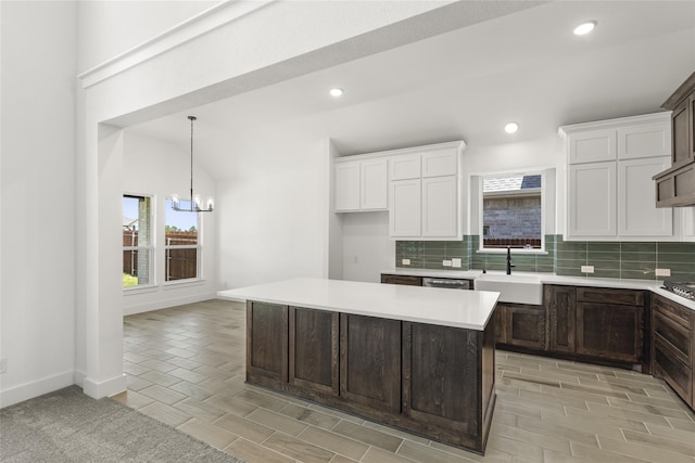 kitchen with a center island, a notable chandelier, sink, white cabinets, and light hardwood / wood-style flooring