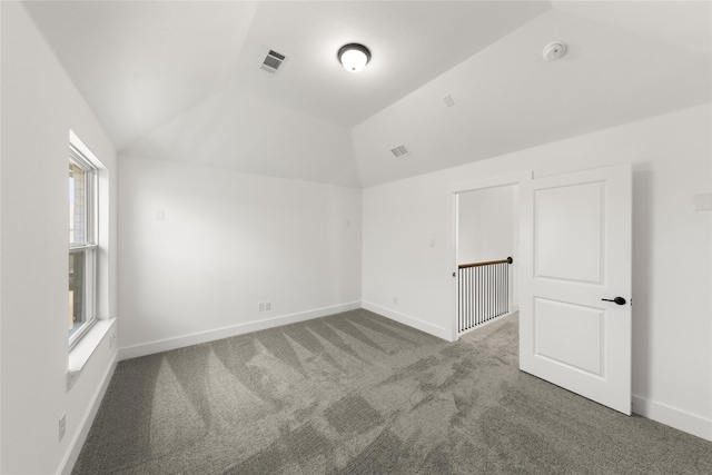 carpeted spare room featuring plenty of natural light and vaulted ceiling