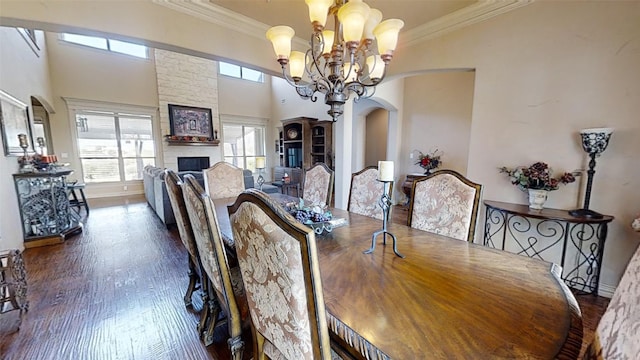 dining area with ornamental molding, a chandelier, a fireplace, and dark hardwood / wood-style flooring