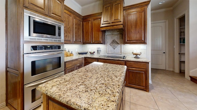 kitchen featuring a center island, light tile patterned flooring, stainless steel appliances, backsplash, and light stone countertops