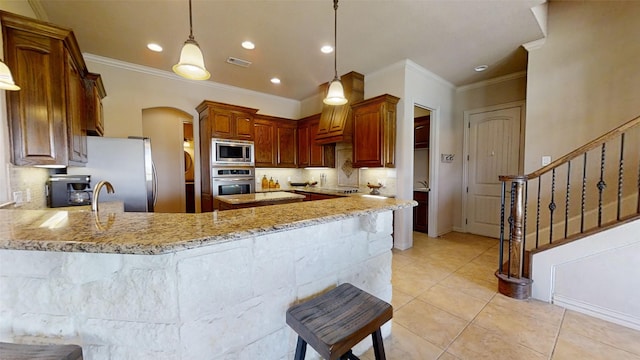 kitchen with kitchen peninsula, light stone countertops, pendant lighting, and stainless steel appliances