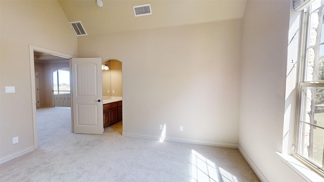 carpeted spare room with high vaulted ceiling