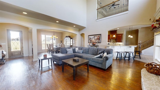 living room with ornamental molding, a towering ceiling, dark hardwood / wood-style flooring, and a chandelier