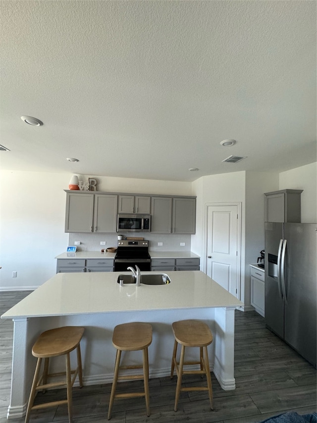 kitchen with gray cabinets, a spacious island, stainless steel appliances, and dark hardwood / wood-style floors