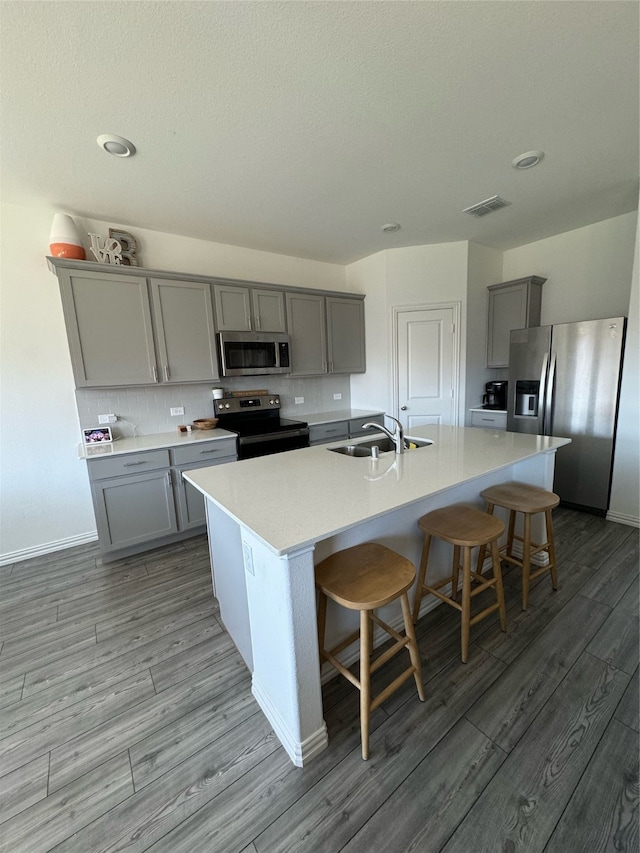 kitchen featuring stainless steel appliances, an island with sink, sink, a breakfast bar area, and light hardwood / wood-style floors