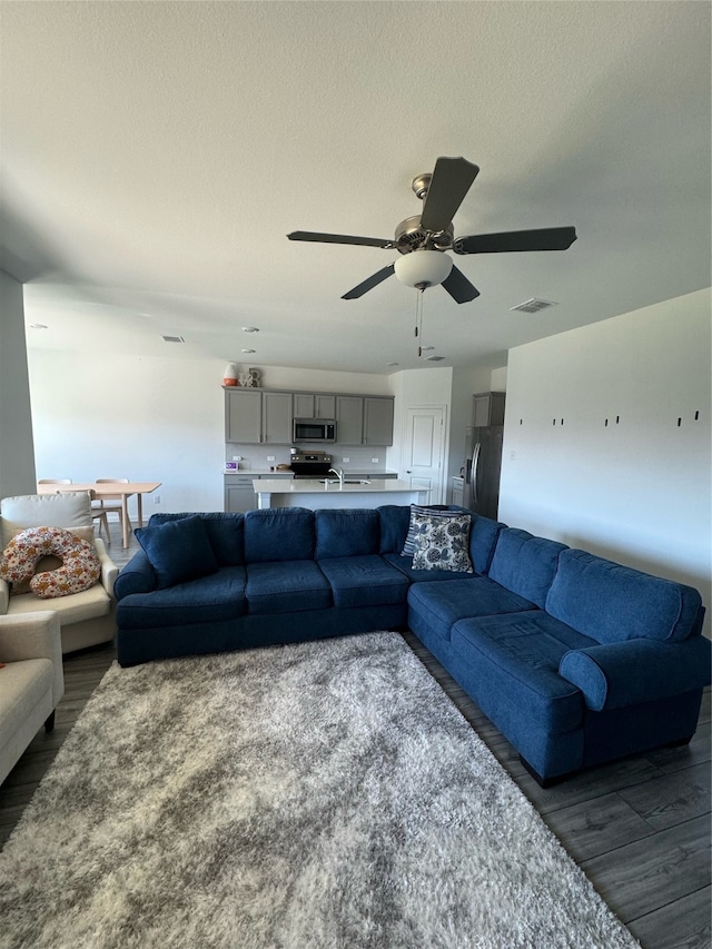 living room featuring a textured ceiling, dark wood-type flooring, and ceiling fan