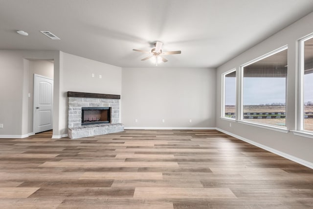 unfurnished living room with ceiling fan, a fireplace, and light hardwood / wood-style floors