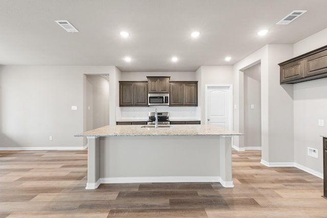 kitchen featuring sink, light stone countertops, and a kitchen island with sink