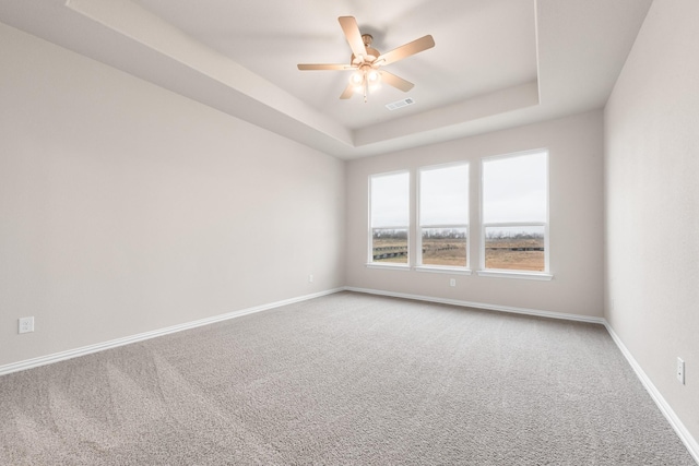 empty room featuring carpet flooring, ceiling fan, and a tray ceiling