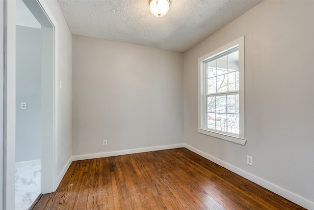 empty room featuring a textured ceiling and dark wood-type flooring