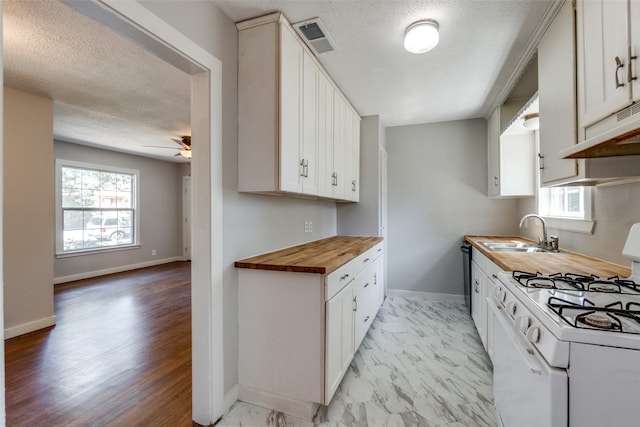 kitchen with gas range gas stove, sink, wooden counters, light wood-type flooring, and white cabinets