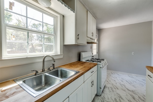 kitchen with white gas stove, wood counters, sink, and white cabinets