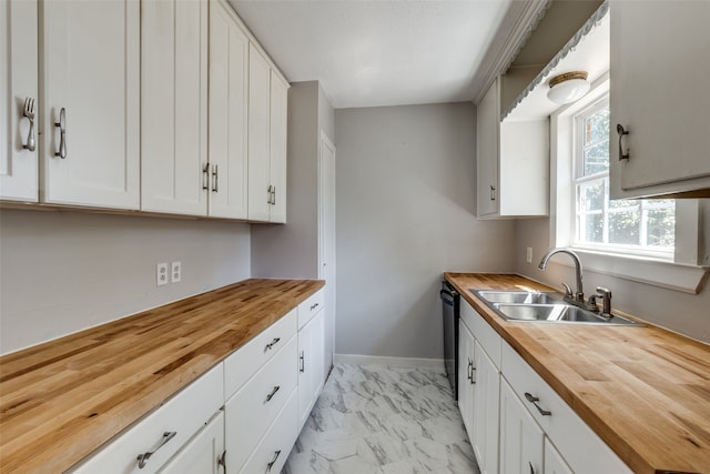 kitchen featuring dishwasher, wooden counters, white cabinetry, and sink