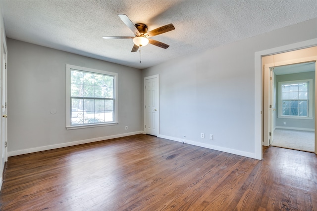 empty room with ceiling fan, dark hardwood / wood-style floors, and a textured ceiling