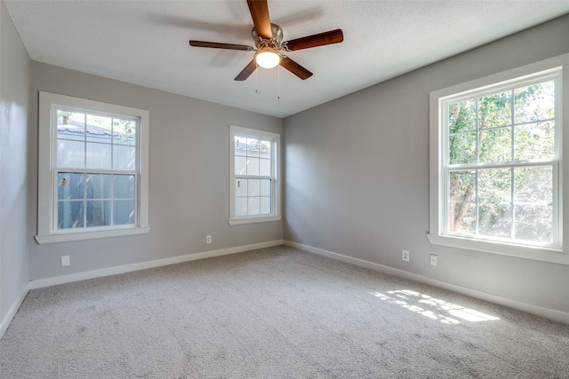 carpeted empty room featuring a textured ceiling, plenty of natural light, and ceiling fan