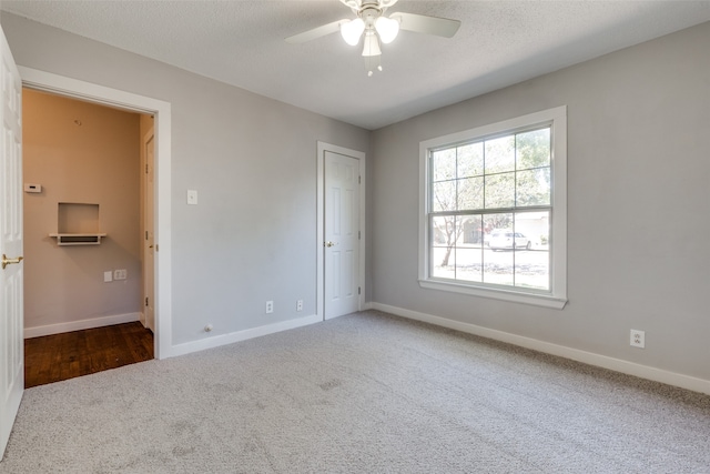 unfurnished bedroom featuring dark carpet, ceiling fan, and a textured ceiling