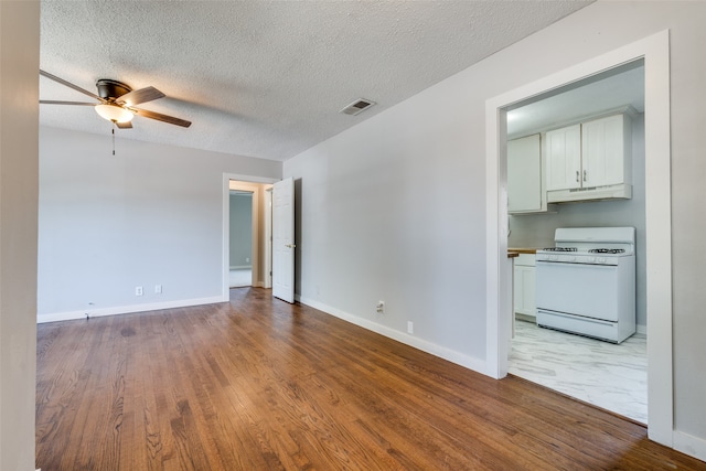 empty room featuring a textured ceiling, wood-type flooring, and ceiling fan