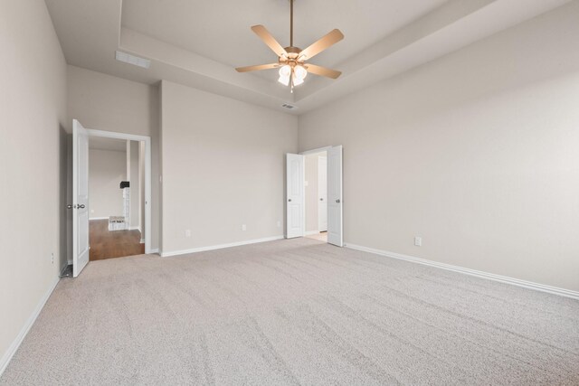 unfurnished bedroom featuring light colored carpet, ceiling fan, and a tray ceiling