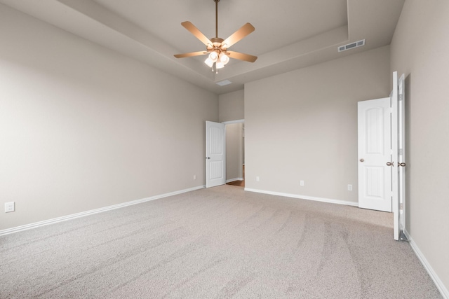 carpeted spare room featuring ceiling fan, a towering ceiling, and a raised ceiling