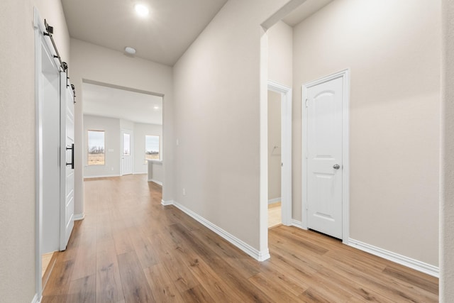 hallway with a barn door and light hardwood / wood-style flooring