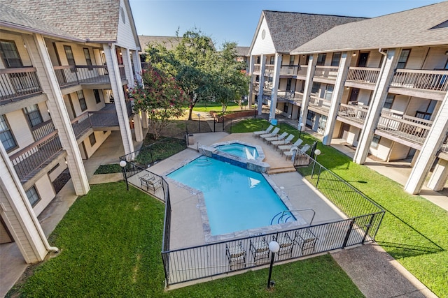 view of swimming pool with a yard and a hot tub