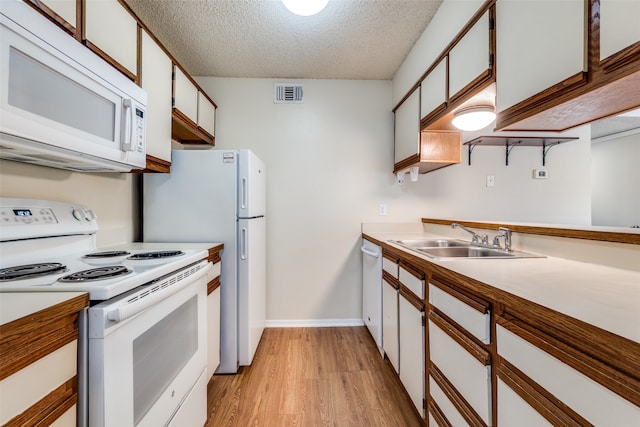 kitchen featuring white cabinets, sink, white appliances, a textured ceiling, and light hardwood / wood-style floors